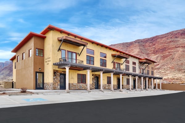 Yellow stucco building with red roof and stone base in arid mountain valley landscape